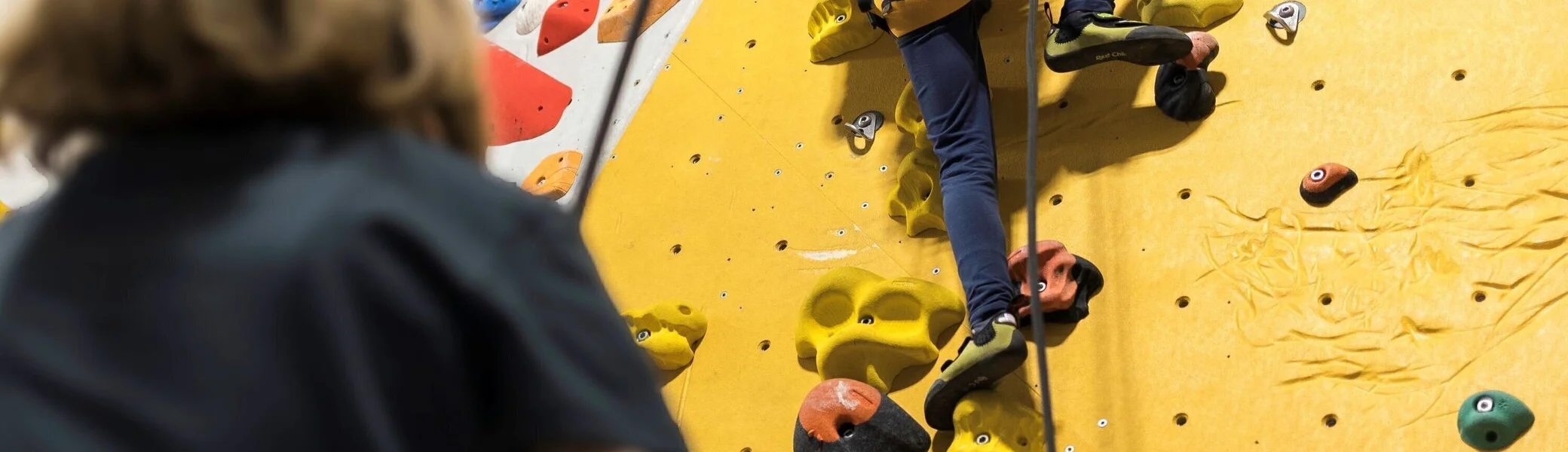 Eine Trainerin sichert ein junges Mädchen in einer Kletterhalle | © DAV / Jens Klatt