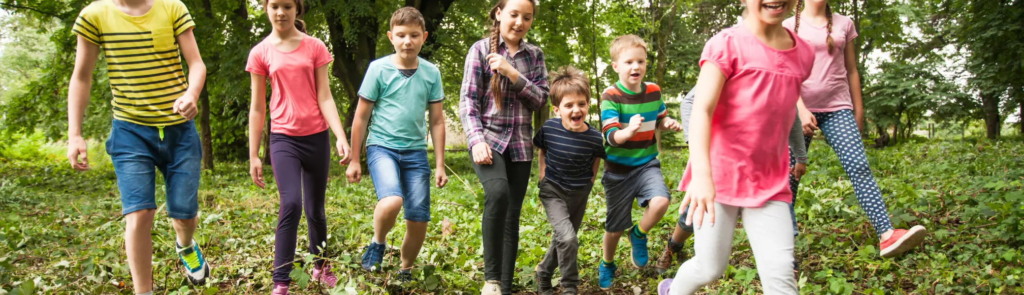 Viele Kinder wandern lachend durch ein Waldgebiet | © Oksix / Adobe Stock